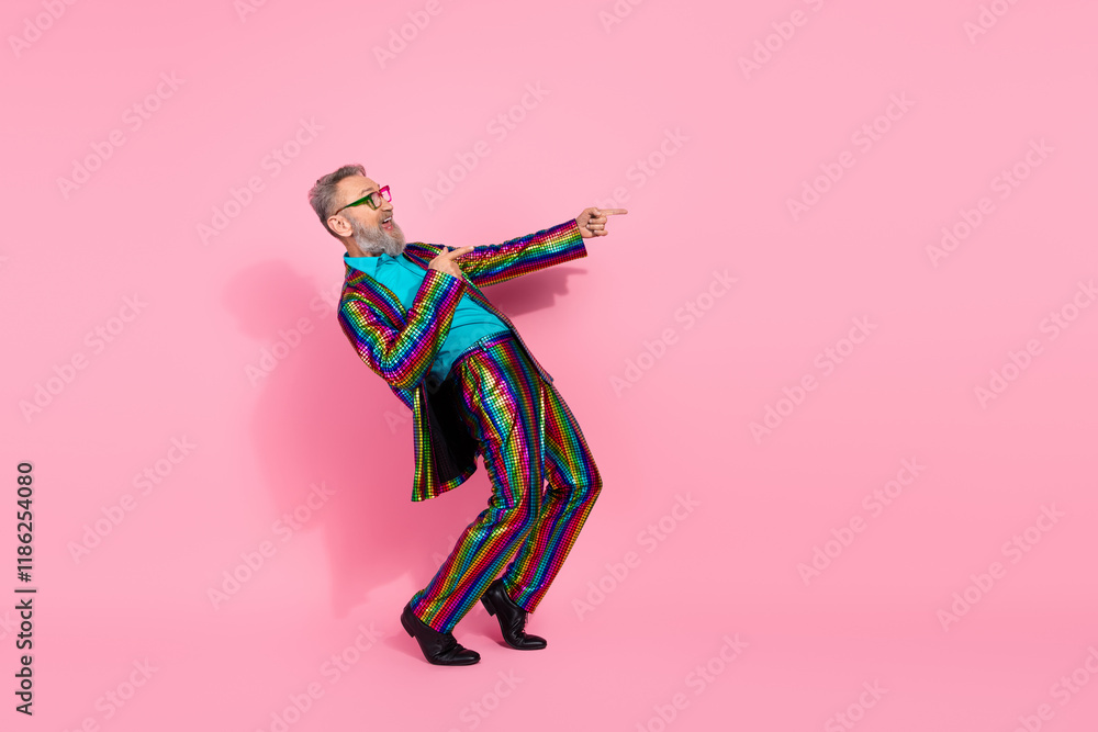 Fototapeta premium Stylish mature man in vibrant suit dancing on a pink background conveying energy and charisma