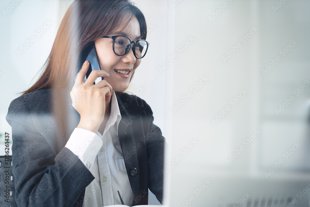 Talking on mobile phone. Close up, smiling asian business woman with eyeglasses using mobile phone, talking to customer during working at office, talking on phone solving business issues Talking on mobile phone. Close up, smiling asian business woman with eyeglasses using mobile phone, talking to customer during working at office, talking on phone solving business issues