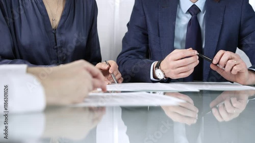Business partners or lawyers are reviewing contract terms during a meeting, negotiating and making decisions together. Business people concept, close up view