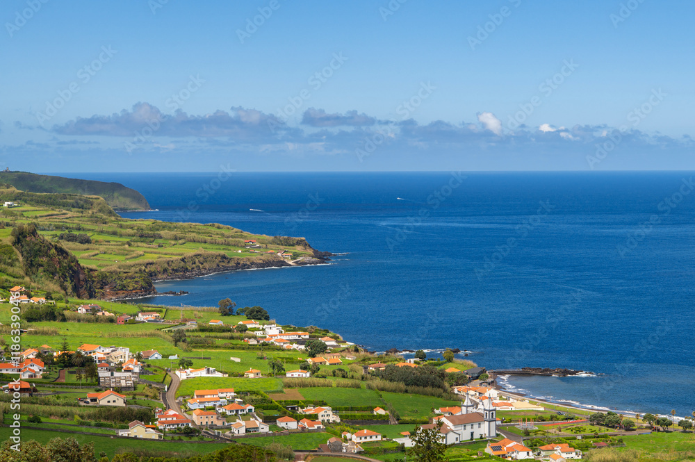 Fototapeta premium Aerial view of Atlantic ocean coastline of Faial Island, Azores, Portugal. White houses, fields, rocks and water. Nature, landscape photography at sunny day.