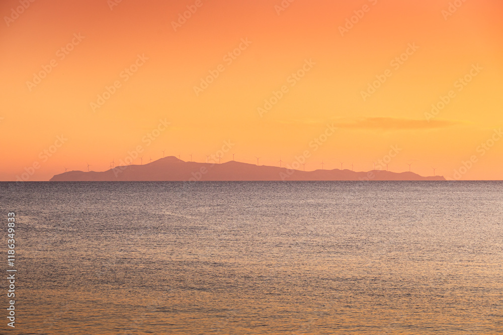 Wind turbines sunset. Seaside landscape with a wind turbine farm on a mountain. Green energy electricity source. Concept image for eco energy.
