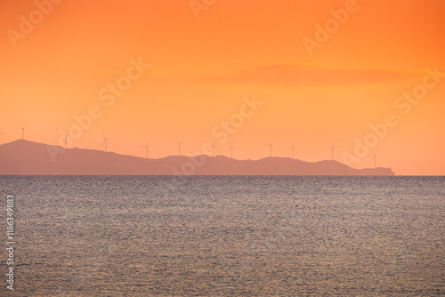 Obraz na płótnie Wind turbines sunset. Seaside landscape with a wind turbine farm on a mountain. Green energy electricity source. Concept image for eco energy. w salonie