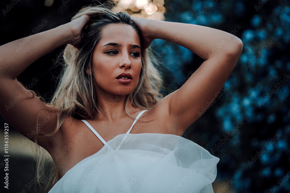 Chica rubia joven posando en jardin con traje blanco