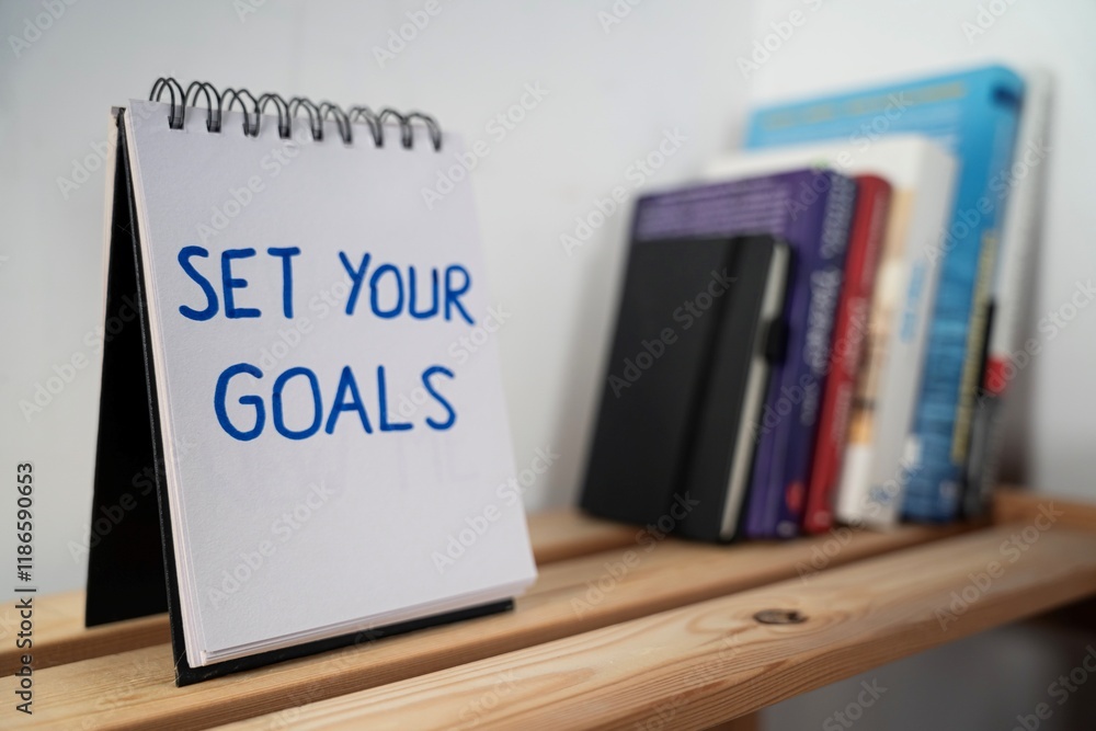 otwarty notes na półce z kartką na której zapisany jest tekst: Set your goals