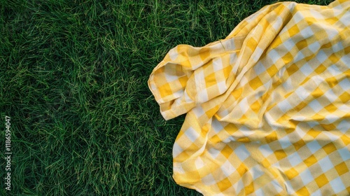 Yellow checkered picnic blanket spread on lush green grass inviting relaxation and outdoor gatherings in a sunny park setting photo