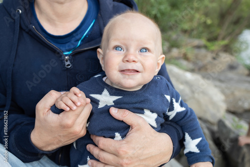 Portrait of a happy little baby 6 months old in the safe hands of an unrecognizable dad. father's day Lifestyle. The happiness of fatherhood photo