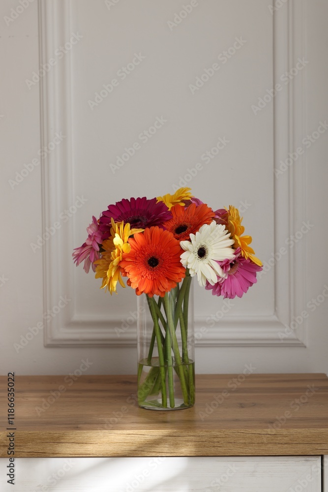Bouquet of beautiful gerbera flowers in glass vase on wooden table indoors Bouquet of beautiful gerbera flowers in glass vase on wooden table indoors