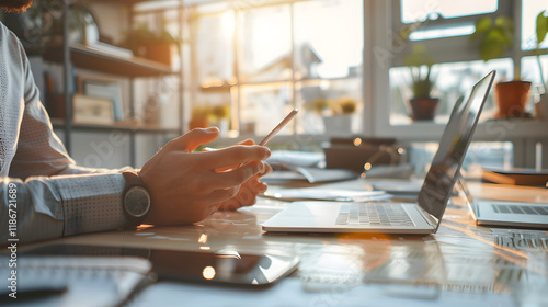 close up of a person hands using mobile phone infront of laptop. modern workspace, business environment