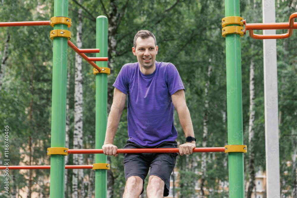Fototapeta premium Man doing push-ups on low bar outdoors