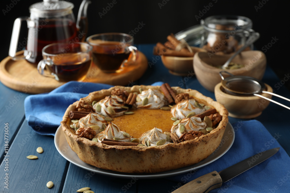 Homemade pumpkin pie with whipped cream, seeds and cinnamon on blue wooden table Homemade pumpkin pie with whipped cream, seeds and cinnamon on blue wooden table