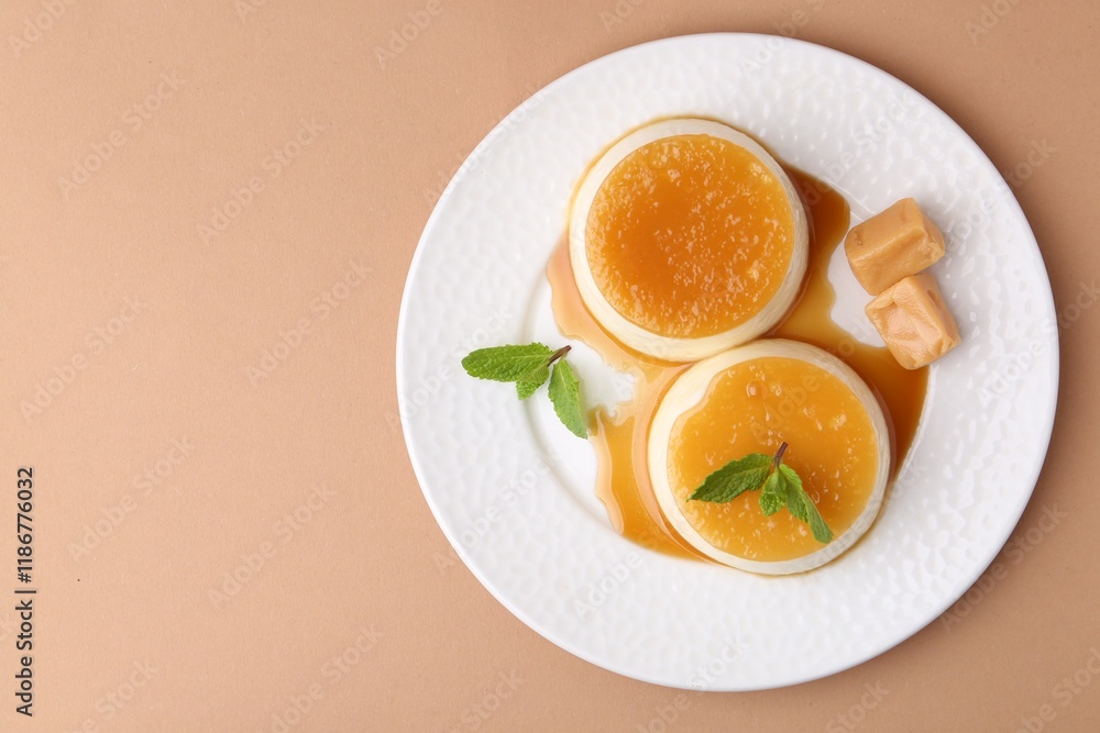 Tasty puddings with caramel sauce served on light brown background, top view. Space for text Tasty puddings with caramel sauce served on light brown background, top view. Space for text