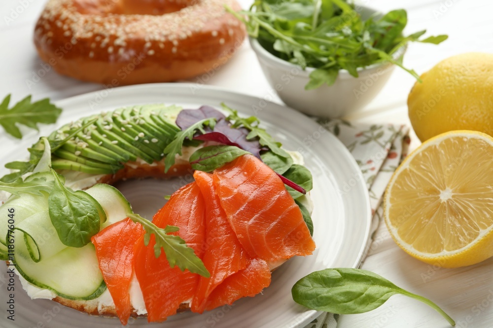 Delicious bagel with salmon, cream cheese, cucumber and avocado on white wooden table, closeup Delicious bagel with salmon, cream cheese, cucumber and avocado on white wooden table, closeup