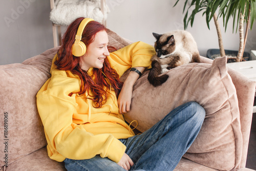 Peaceful teen girl in modern headphones sit relax on comfortable couch listening to music photo