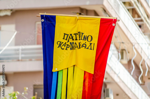 Colorful Striped Flag of Patra City Carnival. Banner Symbol of the Annual Greek Festival is Up in the Sky at the Parade Full of Moving Colorful Sculptures, Masks and Costumes. Greek Words on it. photo