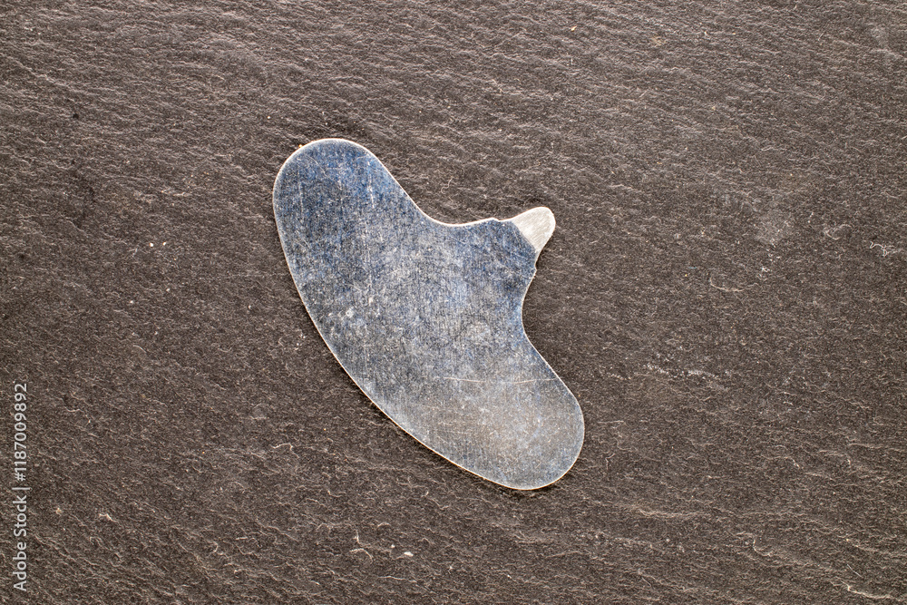 One metal key for macadamia nuts on slate stone, top view. One metal key for macadamia nuts on slate stone, top view.