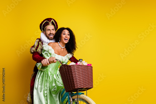 A Couple Dressed as Aristocrats Enjoying a Bicycle Ride on a Bright Yellow Background photo