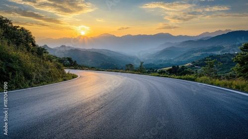 Curved asphalt road winding through lush mountains under a stunning sunset sky with vibrant colors and serene landscape view.