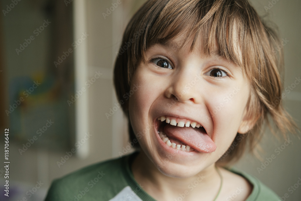 Cheerful funny toddler cute boy is showing tongue making faces at camera, fooling around, joking, aping with silly face, teasing. Preteen child kid 5 years old. Cheerful funny toddler cute boy is showing tongue making faces at camera, fooling around, joking, aping with silly face, teasing. Preteen child kid 5 years old.