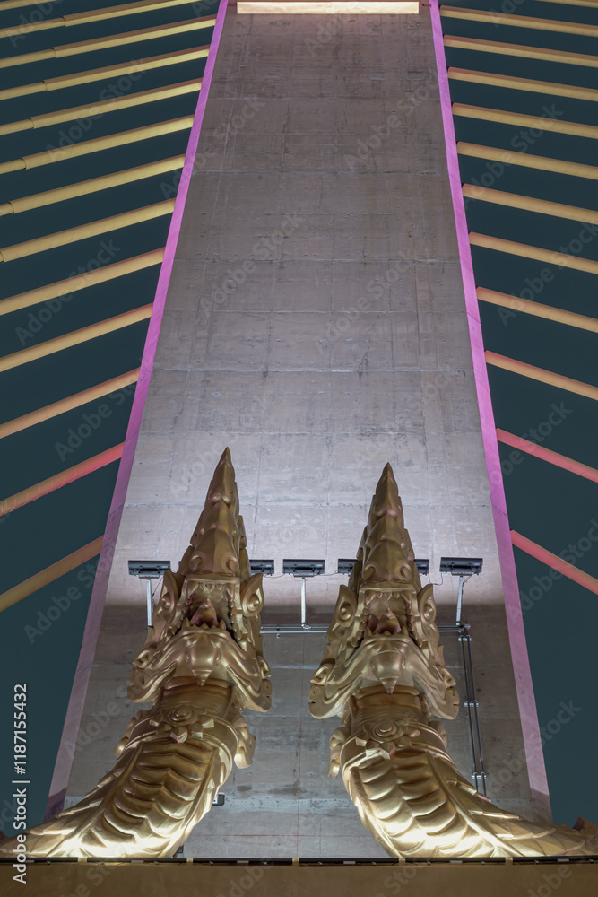 Two golden yellow Naga sculptures on concrete pillars of Thotsamarachan Bridge or the King Rama X Bridge. use it as your Wallpaper, Poster and Space for text, Selective focus.