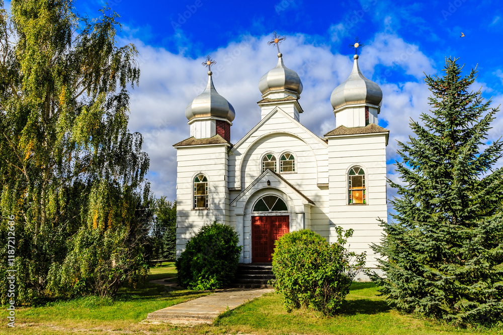 A small white church with a red door sits in a grassy field A small white church with a red door sits in a grassy field