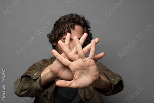 covering face with hand and putting other hand up front to stop camera, refusing photos or pictures