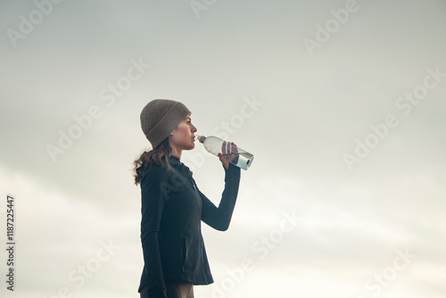 Photos woman drinking from a water bottle outdoors while exercising