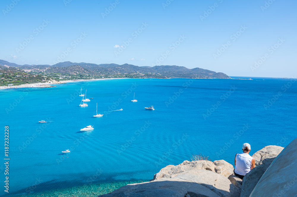 The beautiful view from the Porto Giunco tower overlooking the Gulf of Villasimius with blue sea and boats that seem to fly and a girl admiring it