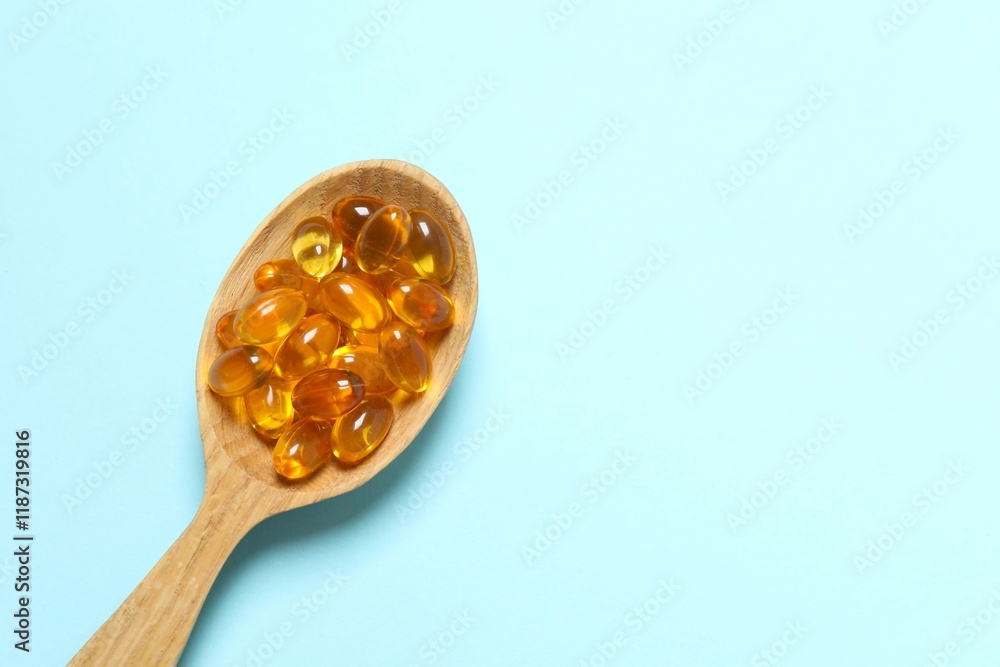 Capsule of omega 3, 6, 9 fish oil, vitamin, food supplement in wooden spoon on color background Capsule of omega 3, 6, 9 fish oil, vitamin, food supplement in wooden spoon on color background
