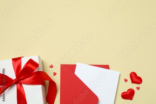 Paper card with envelope, gift box and hearts on color background