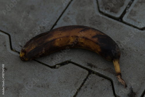 A neglected, discarded banana rests on a paved outdoor surface, drawing attention to the issues of urban waste and environmental challenges photo