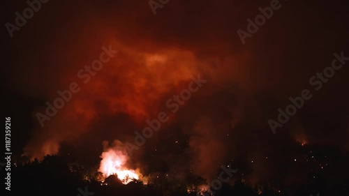 Wallpaper Mural An aerial view shows a forest fire engulfing a hillside, with dense smoke rising and flames visible among the trees. The video the destructive power of the fire and its effect on the environment Torontodigital.ca