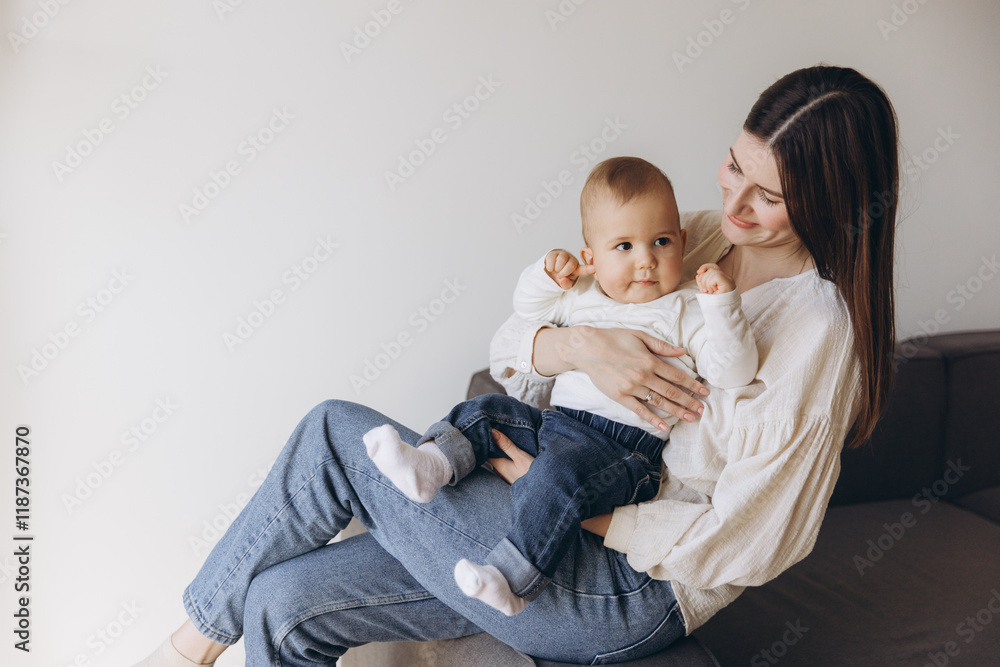 Mother holding her baby while sitting on a sofa