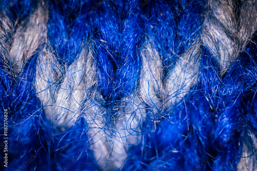 Obraz premium A detailed macro shot of blue and white knitted fabric, showcasing the soft texture and intricate weave of the yarn. The color contrast highlights the artistic pattern.