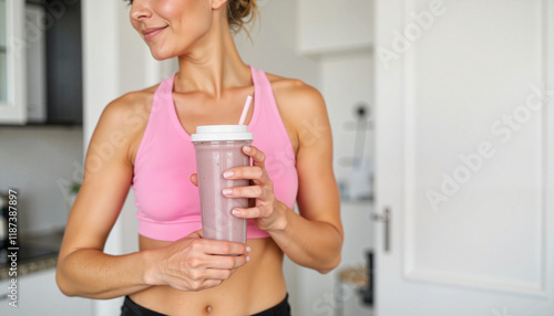 Fitness woman enjoying protein shake in bright kitchen, healthy lifestyle