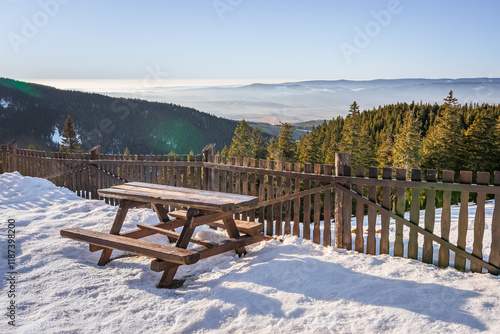 Eastern Sudetes, resting place with table and bench, viewpoint on mountain hiking trail, winter landscape in mountains on sunny day.