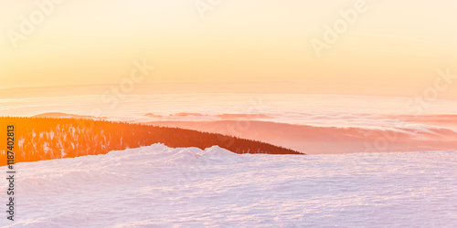 Fototapeta Naklejka Na Ścianę i Meble -  Eastern Sudetes, view of mountain range with thick fog in valley from peak from hiking trail during winter hike in mountains, viewpoint of wide winter landscape in mountains at orange sunset.