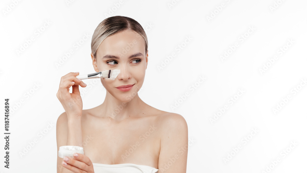A serene woman gently massages facial cream into her skin, enjoying a peaceful moment during her skincare routine. Ideal for promoting beauty, skincare, cosmetology advertising. Free copy space A serene woman gently massages facial cream into her skin, enjoying a peaceful moment during her skincare routine. Ideal for promoting beauty, skincare, cosmetology advertising. Free copy space