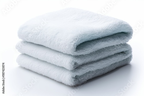 Soft and fluffy white towels neatly stacked on a clean surface in a bright indoor setting