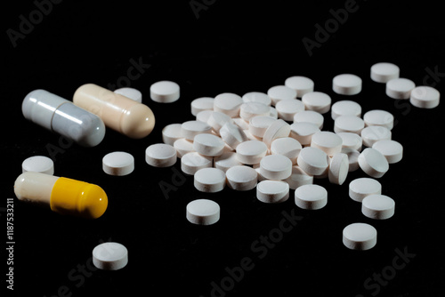 White round tablets are scattered on a black background.