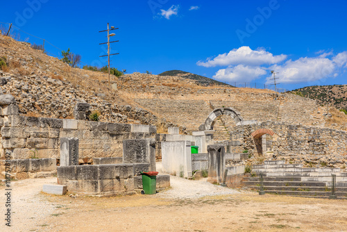 A stone building with a green trash can in front of it. Ruins of the ancient city of Philippi, Greece photo