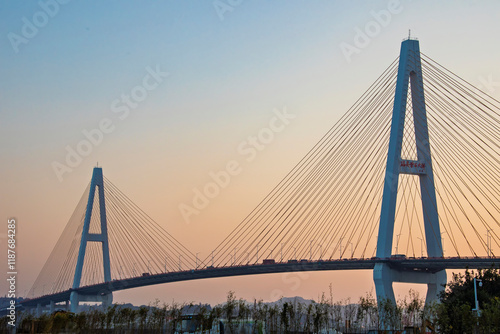 The sunset and view of Shantou Queshi Bridge at Xidi Park Shantou China is a breathtaking sight. As the sun dips below the horizon, the sky transforms into a palette of warm hues.  photo