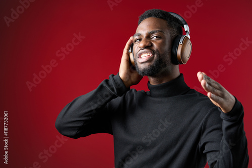 Happy young man enjoying music with headphones against a vibrant red background, expressing joy and energy, perfect for music and lifestyle themes photo