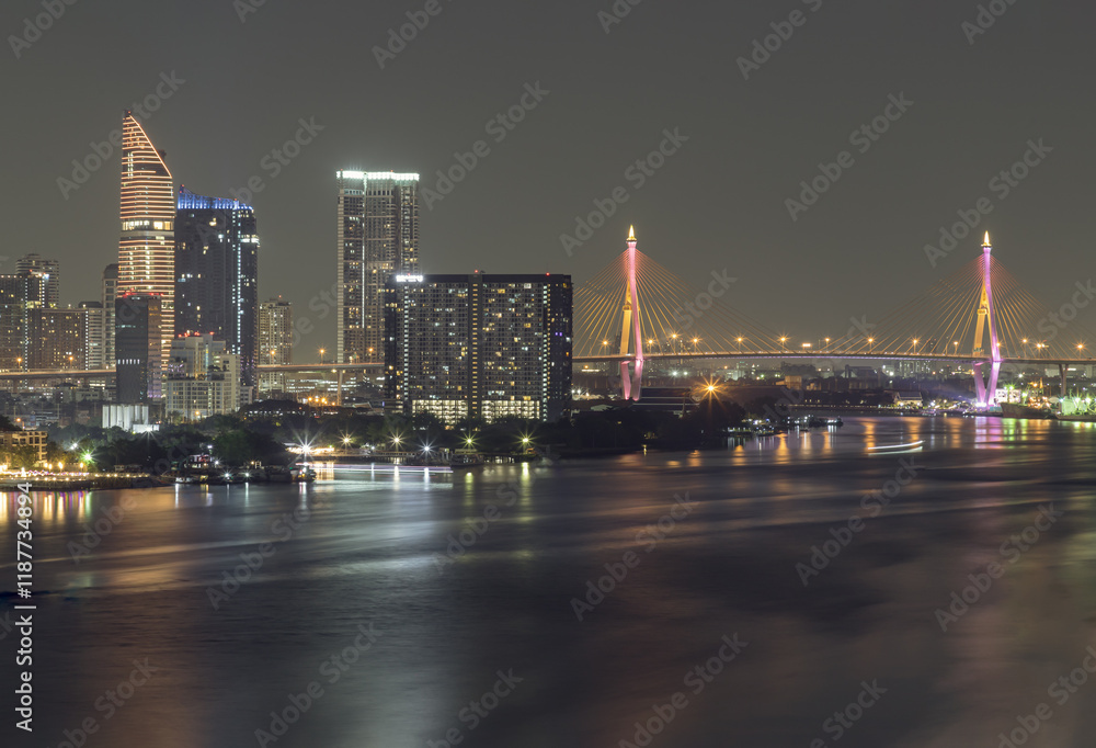 Nightscape city view with bright glowing lighting of Skyscrapers and Bhumibol bridge with Chao phraya river in the foreground. City scenery night of Bangkok in the sundown, use it as wallpaper, Poster