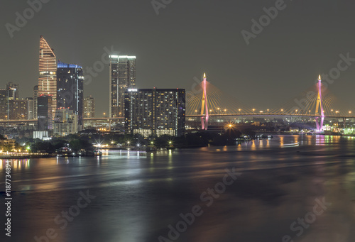 Obraz na płótnie Nightscape city view with bright glowing lighting of Skyscrapers and Bhumibol bridge with Chao phraya river in the foreground. City scenery night of Bangkok in the sundown, use it as wallpaper, Poster w salonie
