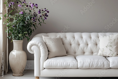  A white minimalist sofa with decorative cushions and a floral vase, perfect for serene interiors. 