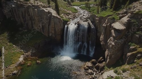 Majestic waterfall cascading into a serene pool in rocky landscape surrounded by lush greenery