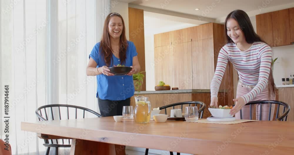 Setting table, asian mother and daughter preparing meal together in modern kitchen Setting table, asian mother and daughter preparing meal together in modern kitchen