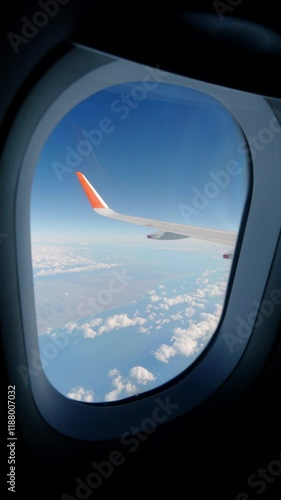 Aerial view of blue sea and sky through a window of an airplane, Travel or sightseeing, Vertical video for smartphone footage