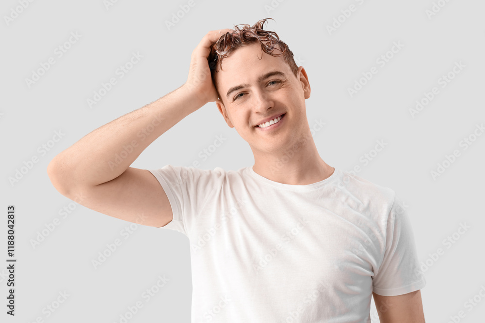 Young man washing hair against light background Young man washing hair against light background