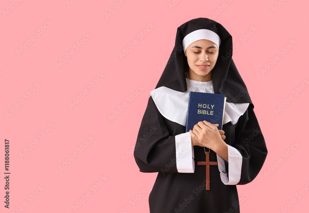Young nun with Bible on pink background Young nun with Bible on pink background